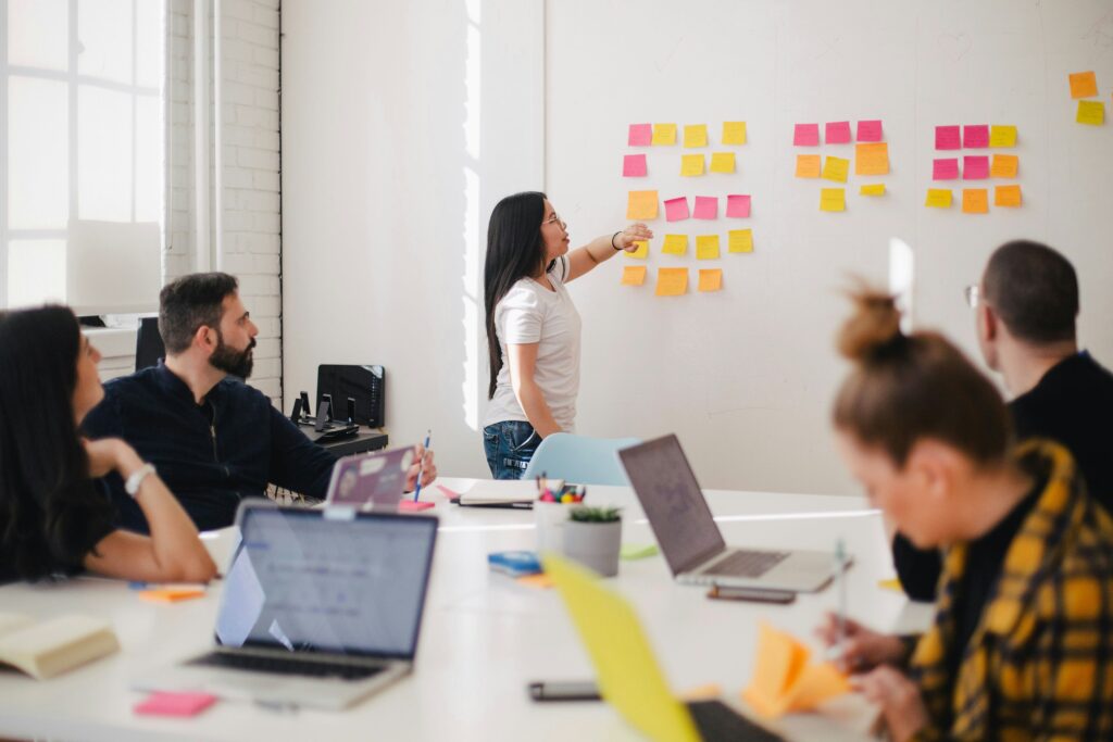 A group of people meeting together with a white board and sticky notes