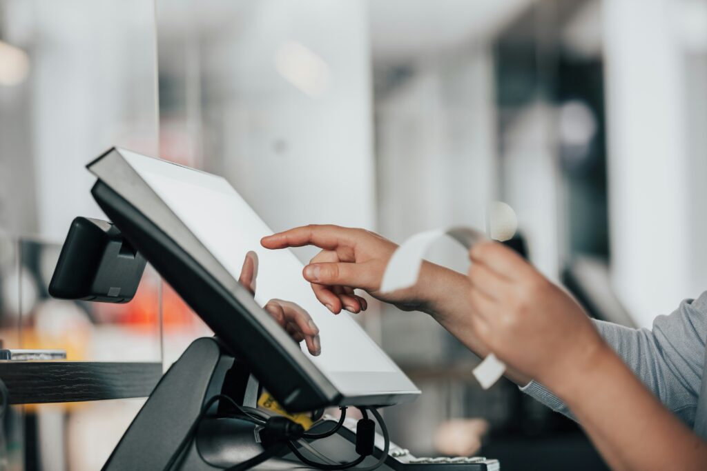 Hands of person holding a receipt and entering data into a register